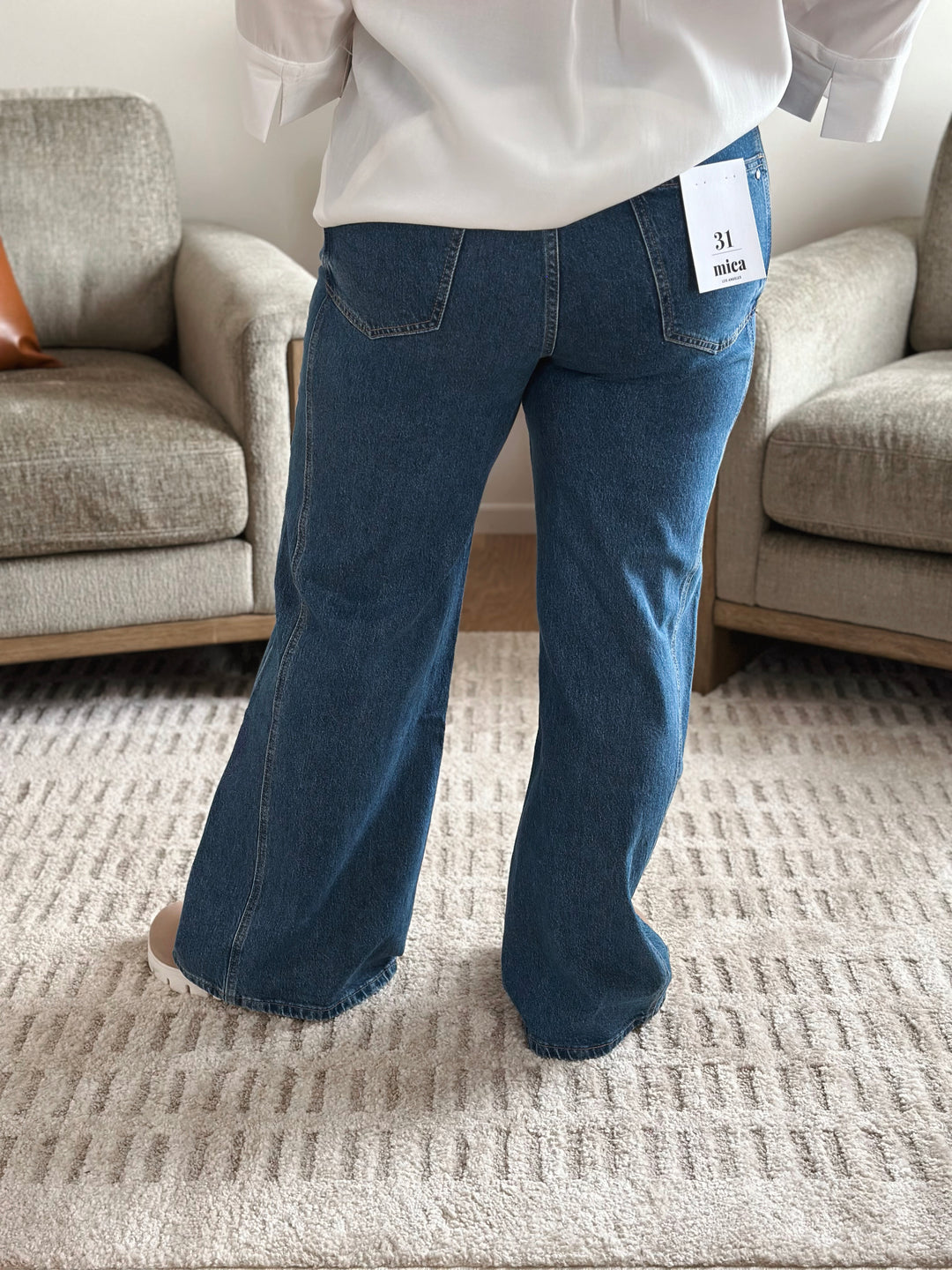 Person wearing blue jeans with a white shirt in a living room setting