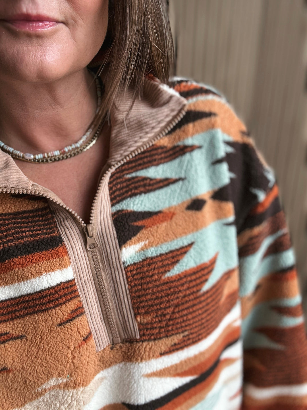 Person wearing a patterned pullover with a neutral background