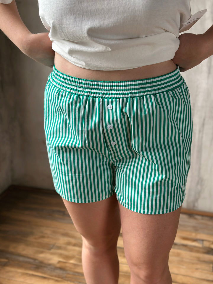 Green and white striped shorts worn by a person indoors.