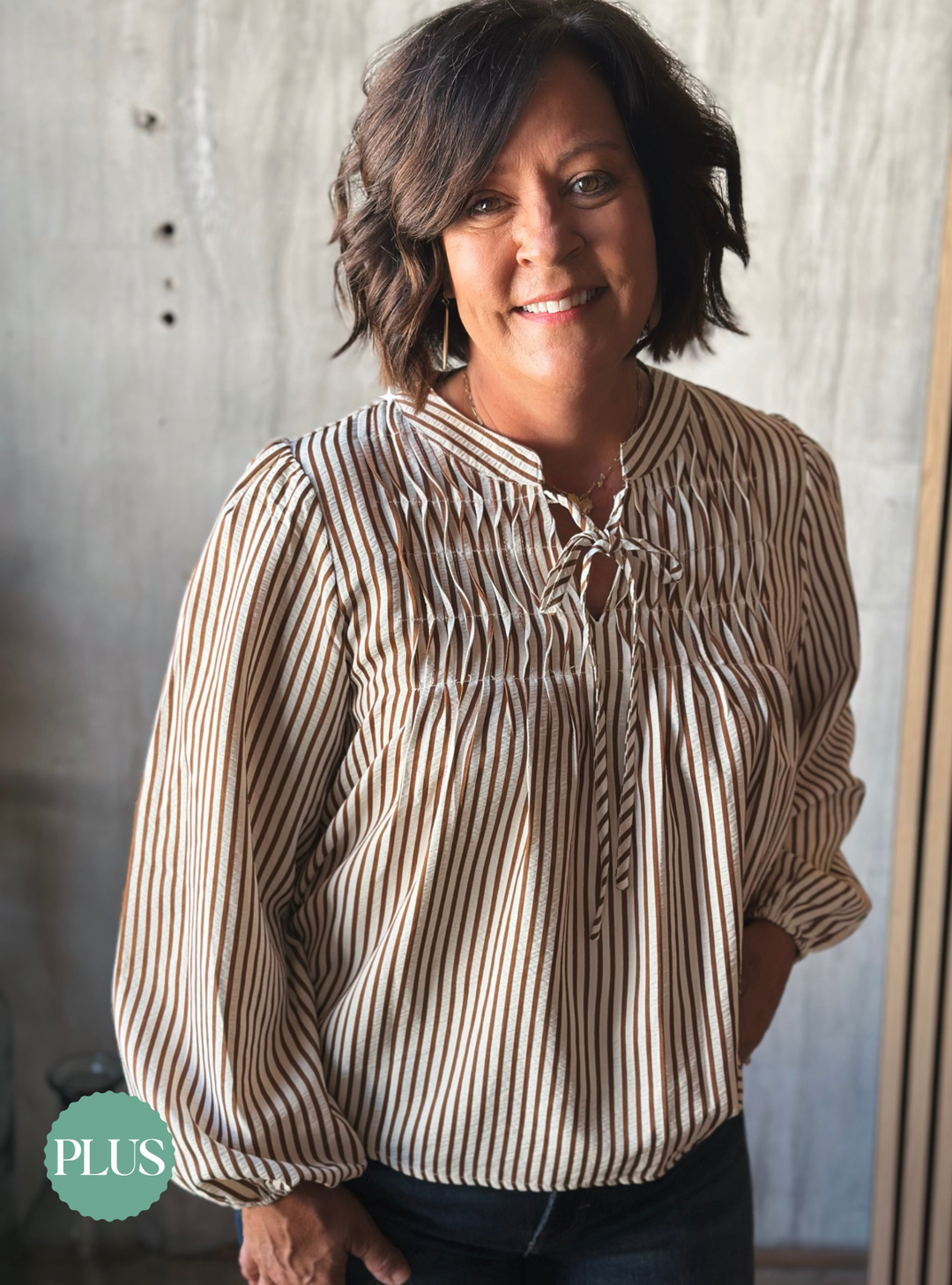 Woman wearing a striped blouse standing against a neutral background