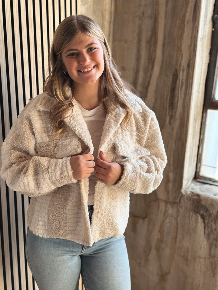 Woman wearing a beige fleece jacket in a rustic setting