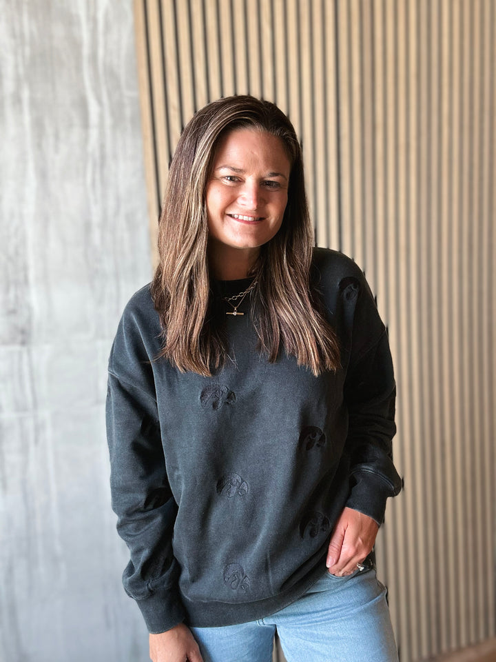 Person wearing a black sweatshirt standing against a textured wall.
