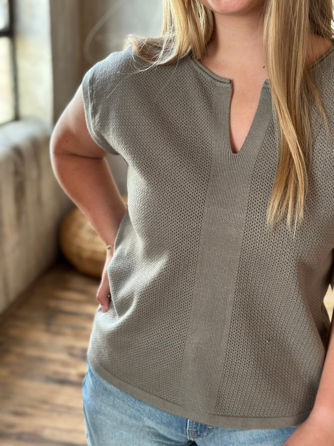Woman wearing a beige v-neck top in an indoor setting.