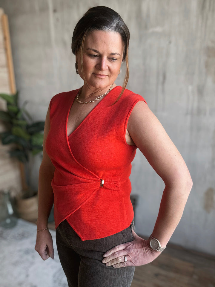 Woman wearing a red sleeveless top in an indoor setting.