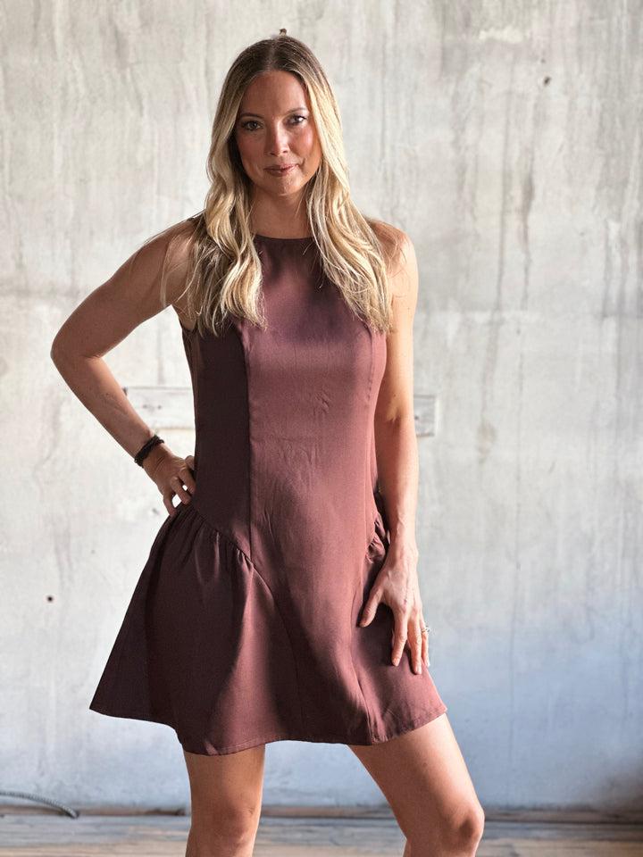 Woman wearing a brown dress against a plain background
