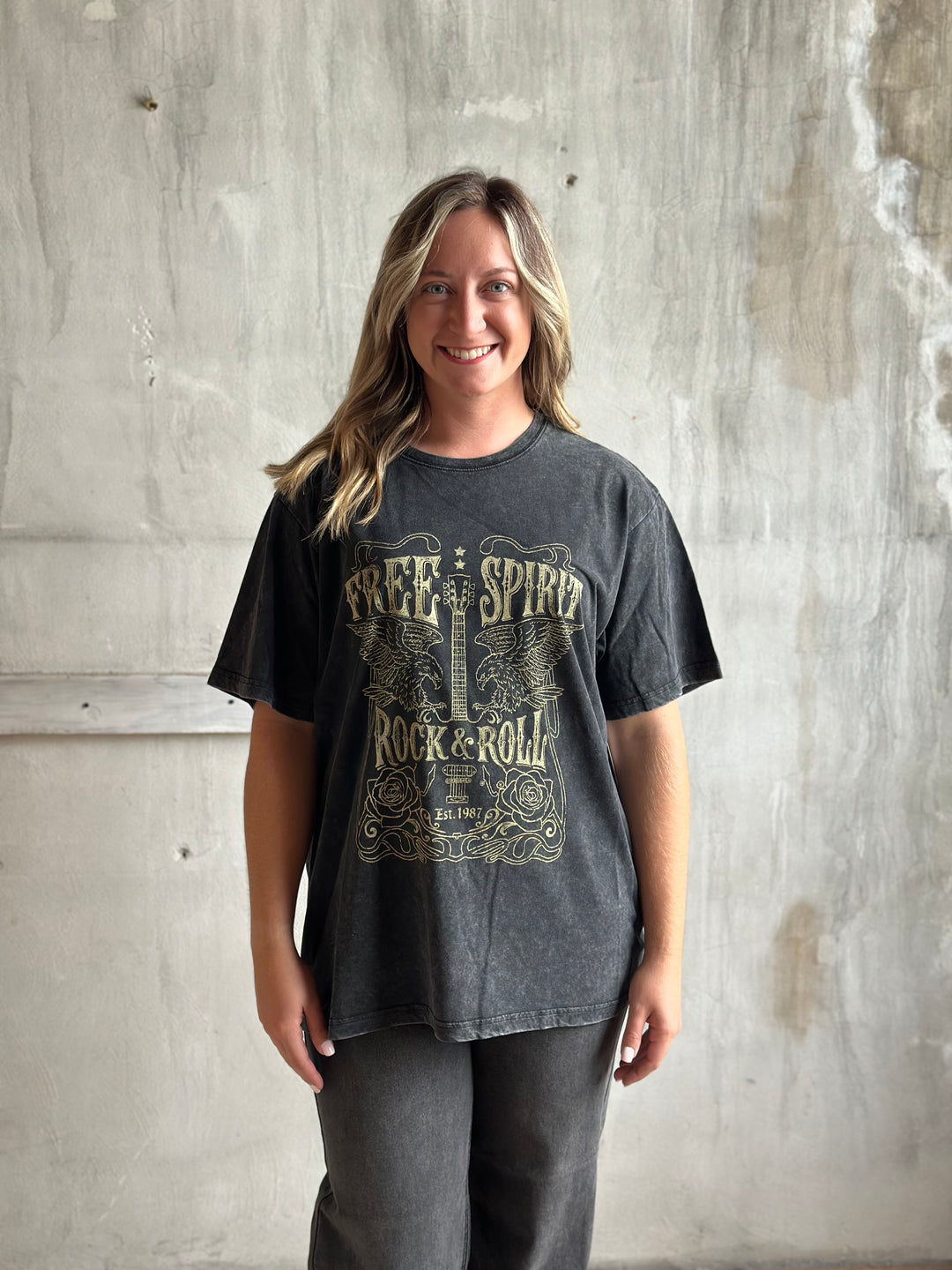 Woman in a charcoal graphic tee and gray jeans, full view