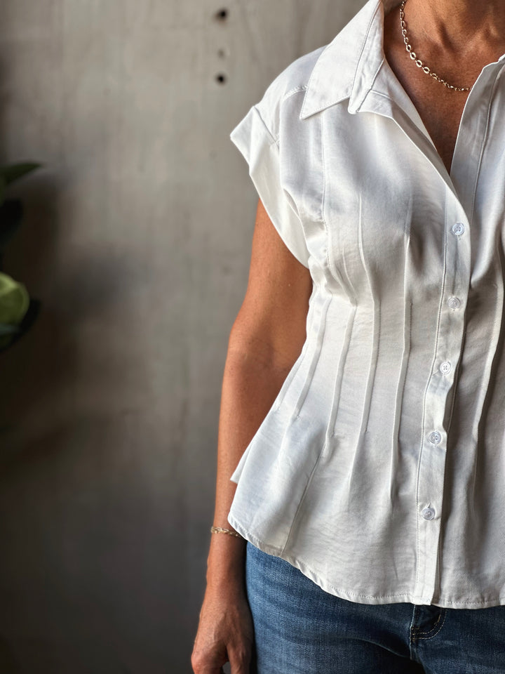 Person wearing a white short-sleeve shirt against a neutral background