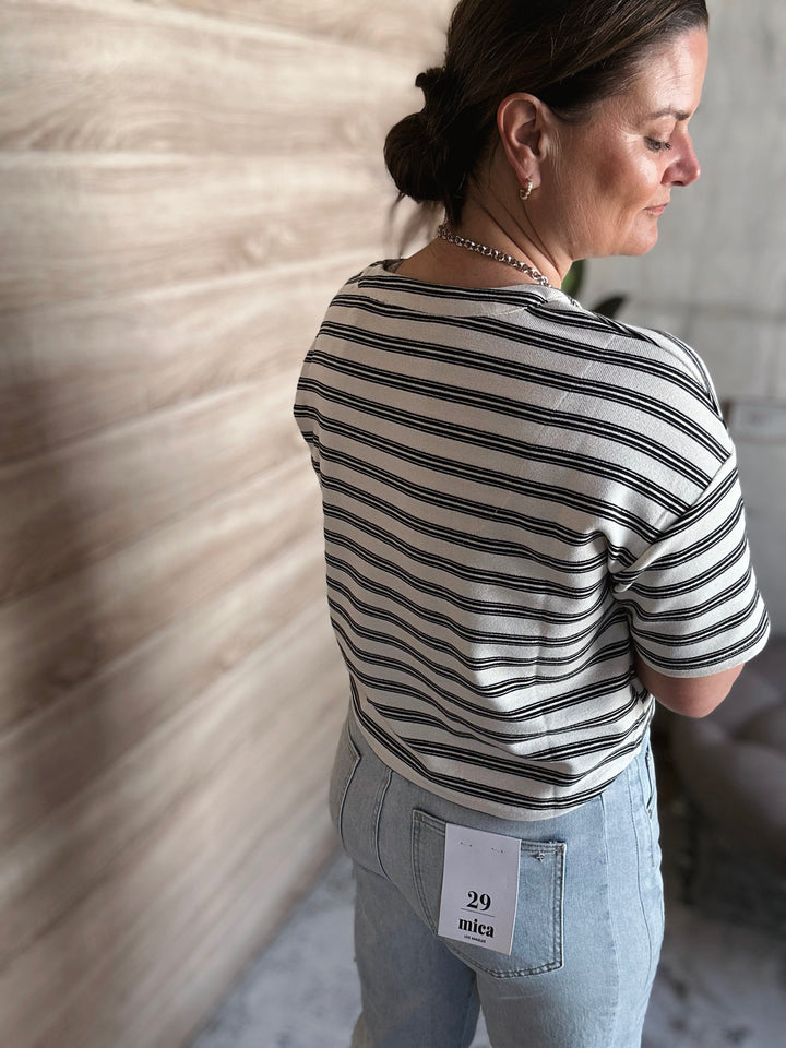 A woman wearing a short sleeved black and white striped shirt. 