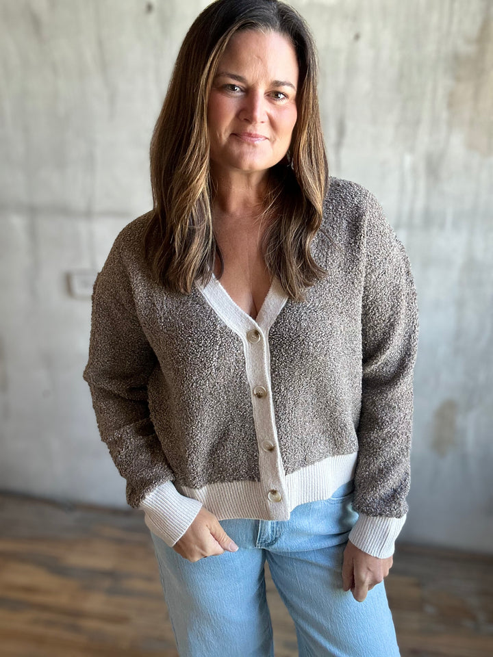 Woman wearing a brown speckled knit V-neck cardigan with cream trim