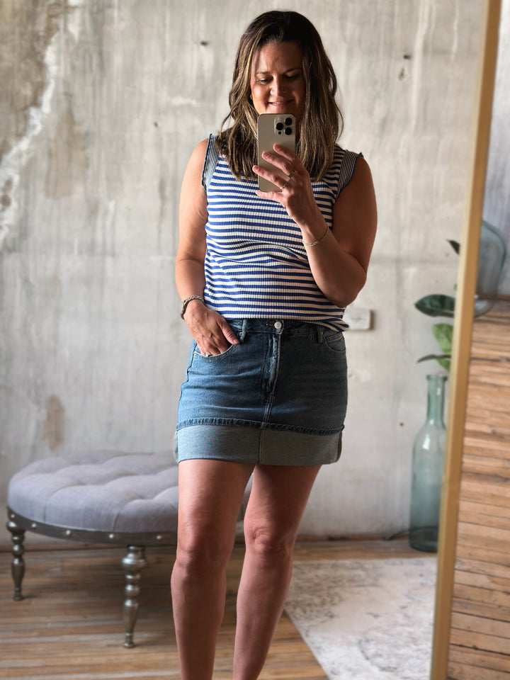 Woman wearing a blue and white striped tank top and a denim skirt.