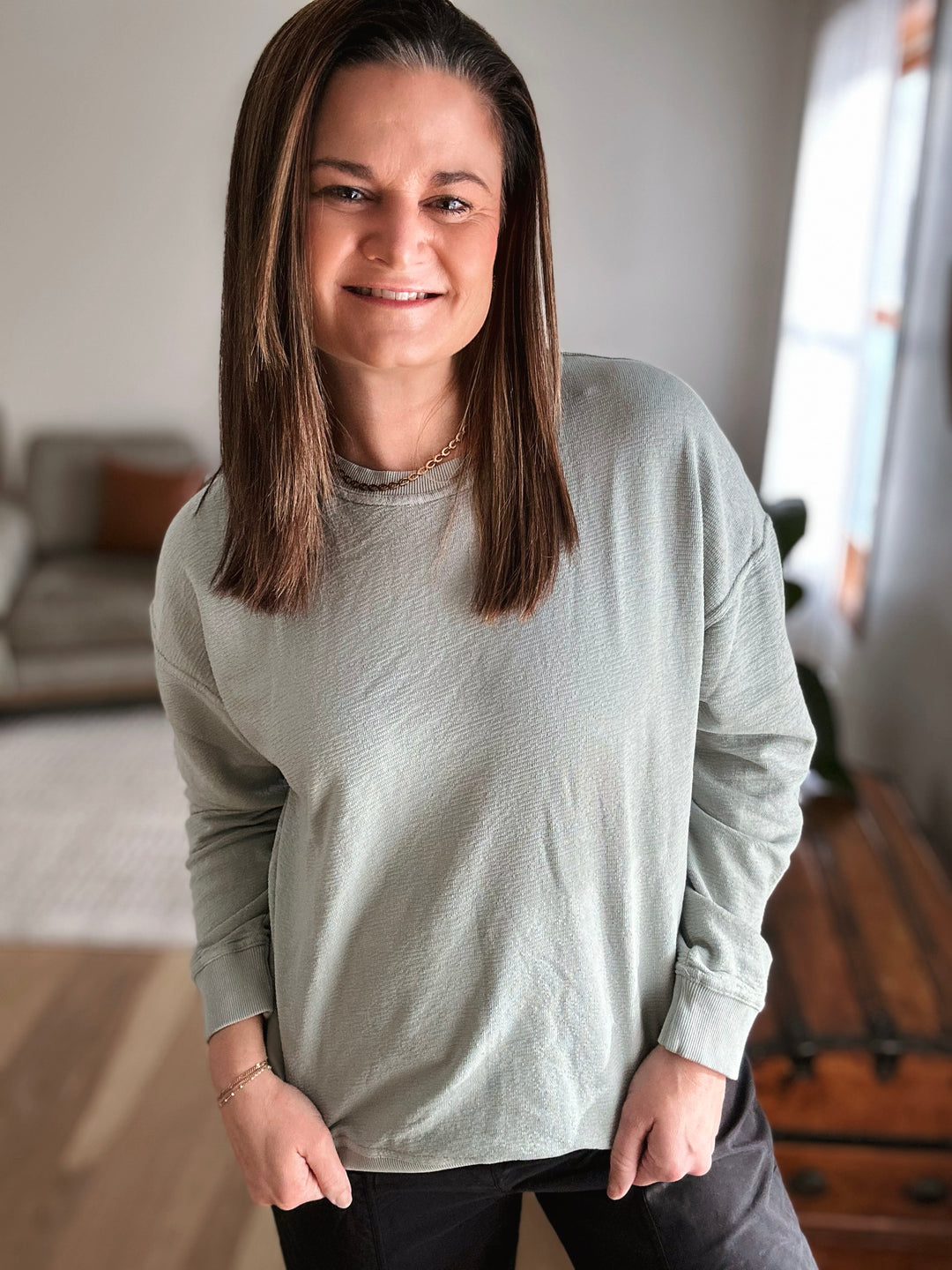 Woman wearing a light gray long-sleeve shirt in a home setting