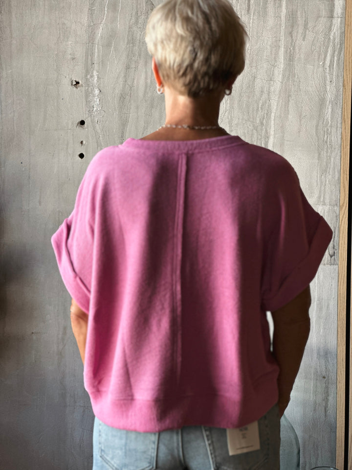 Person wearing a pink sweater with a gray wall background