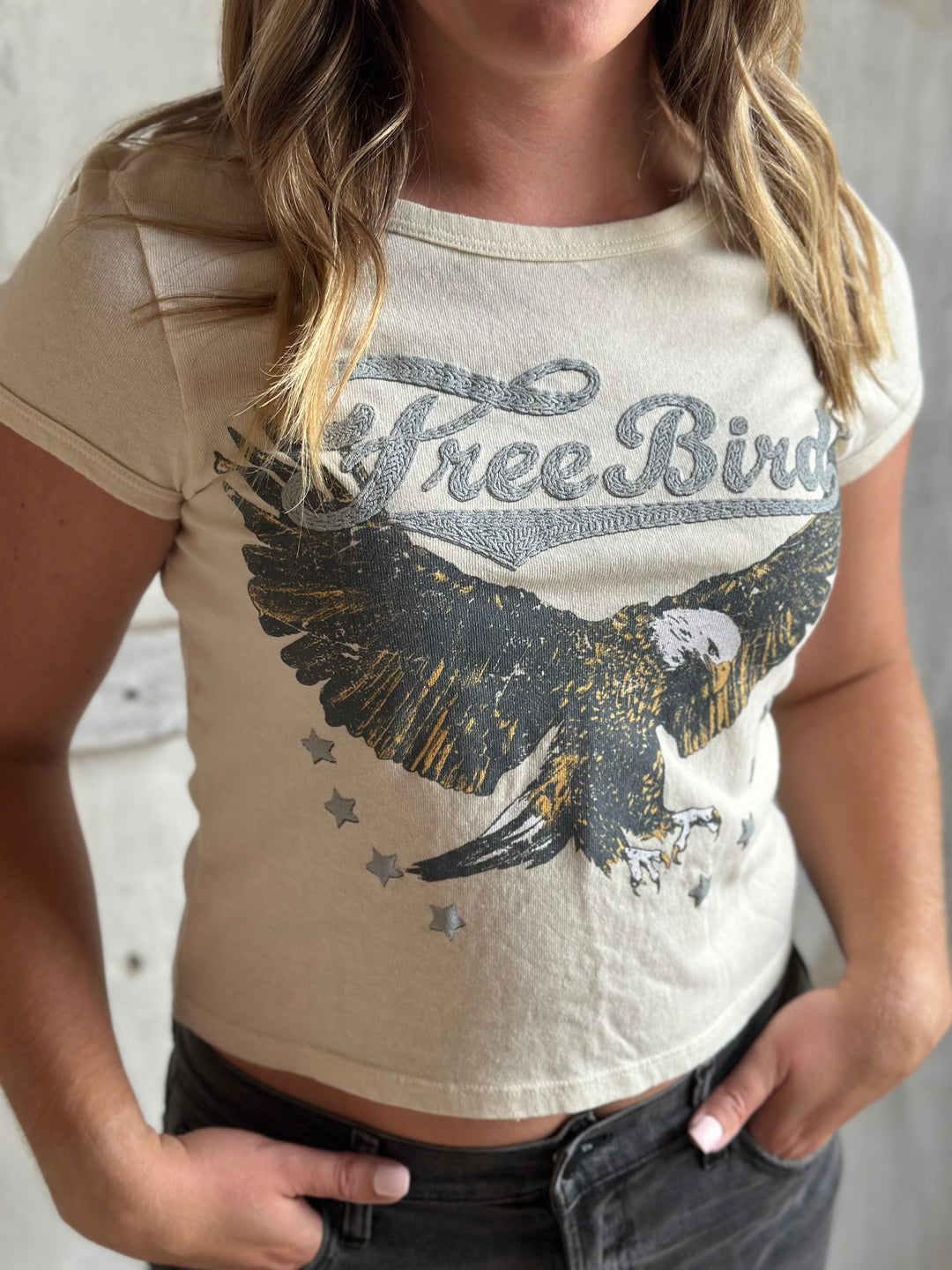 Close-up of a cream fitted tee with a Free Bird eagle print