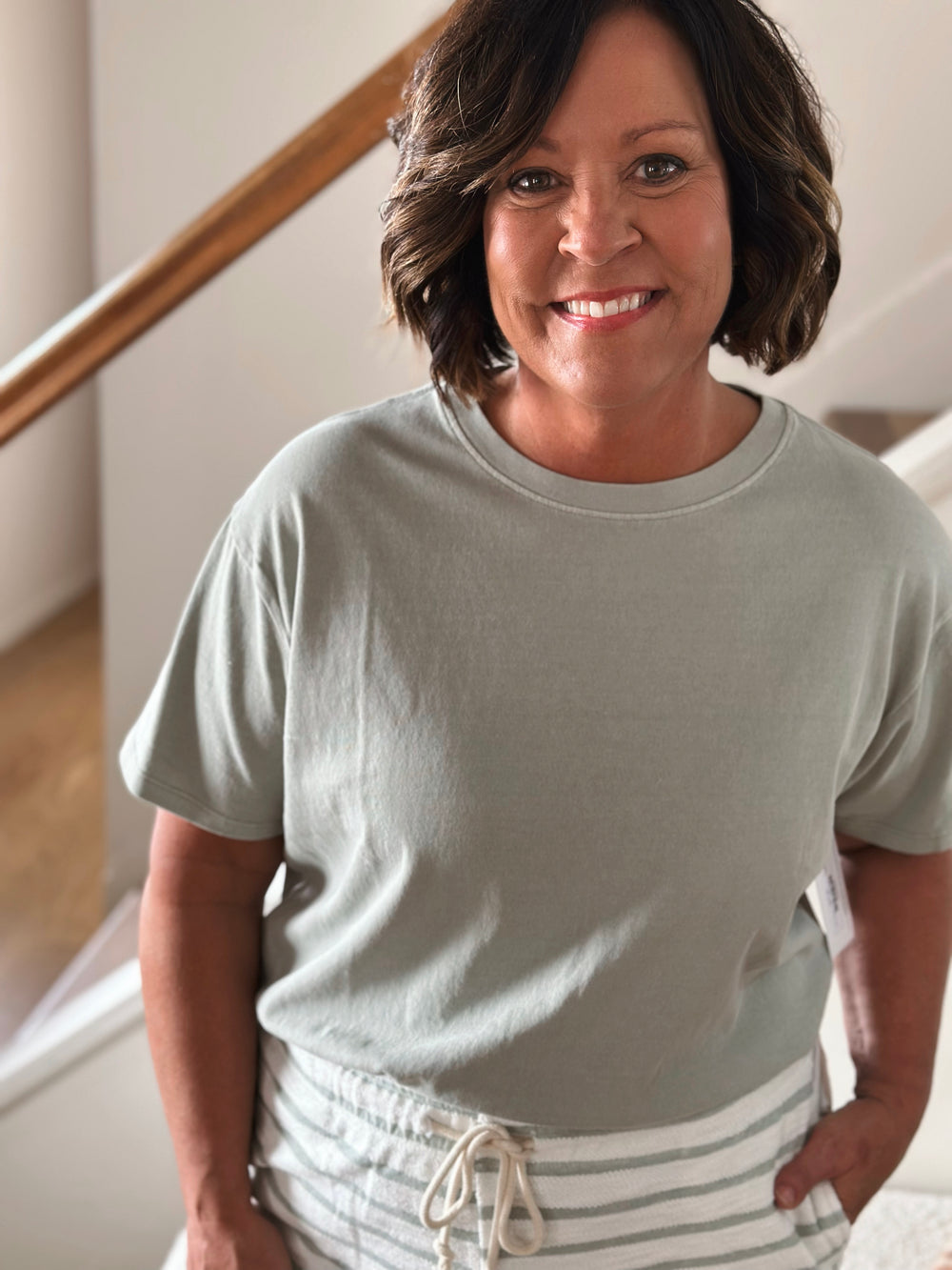 Woman wearing a light green t-shirt and striped pants facing forward.