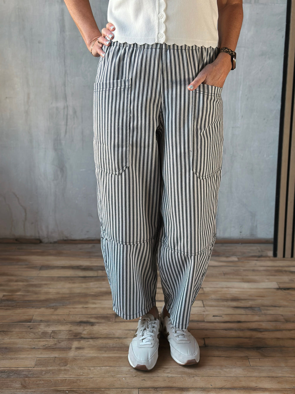 Person wearing black and white striped pants with a plain background