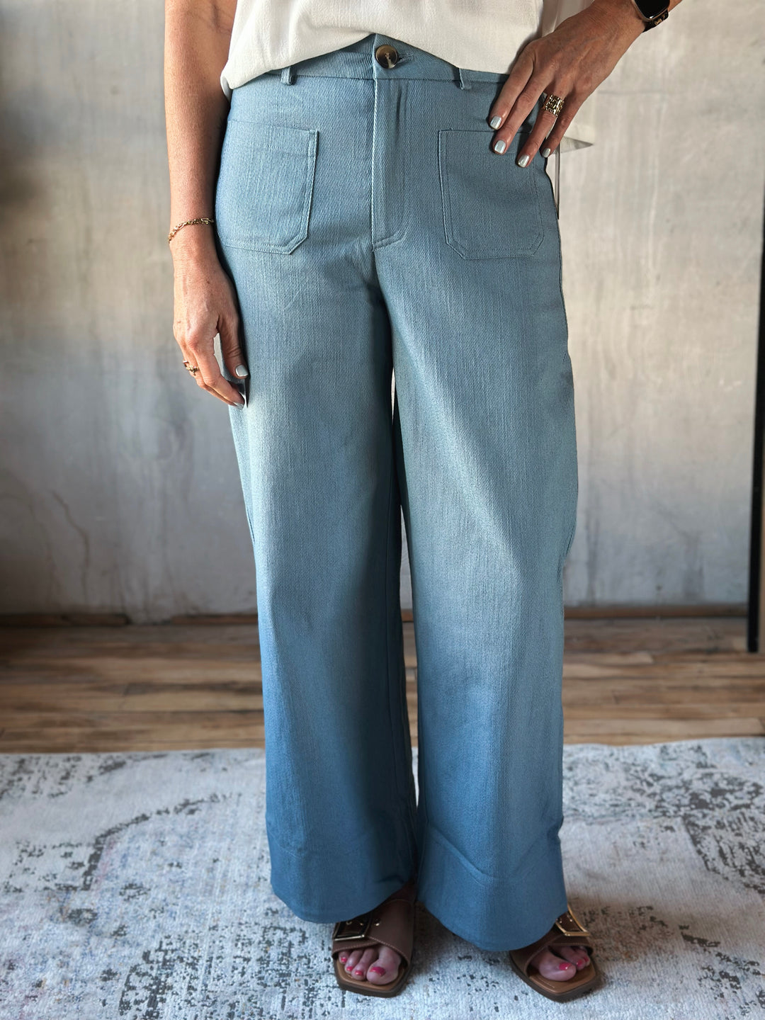 Person wearing light blue wide-leg pants standing on a rug with a neutral background