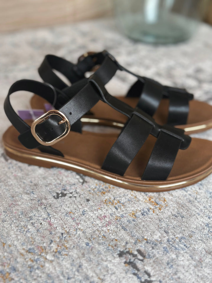 Black strappy sandals on a textured surface.