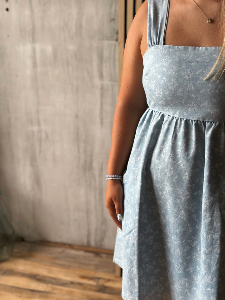 Person wearing a light blue dress with a neutral background