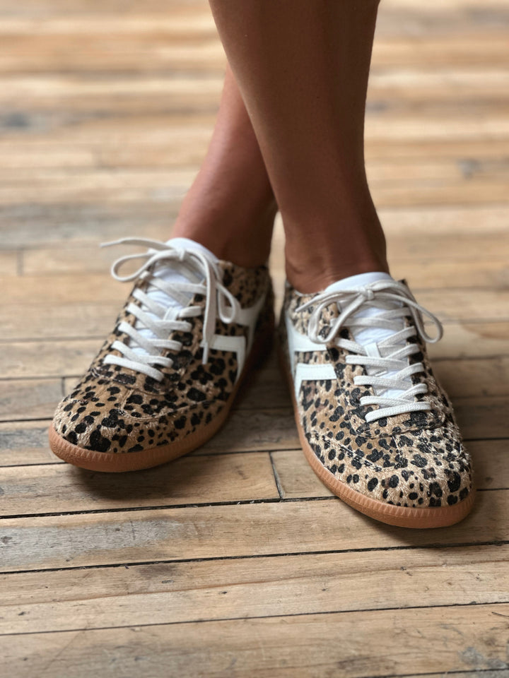 Leopard print sneakers with white laces on a wooden floor.