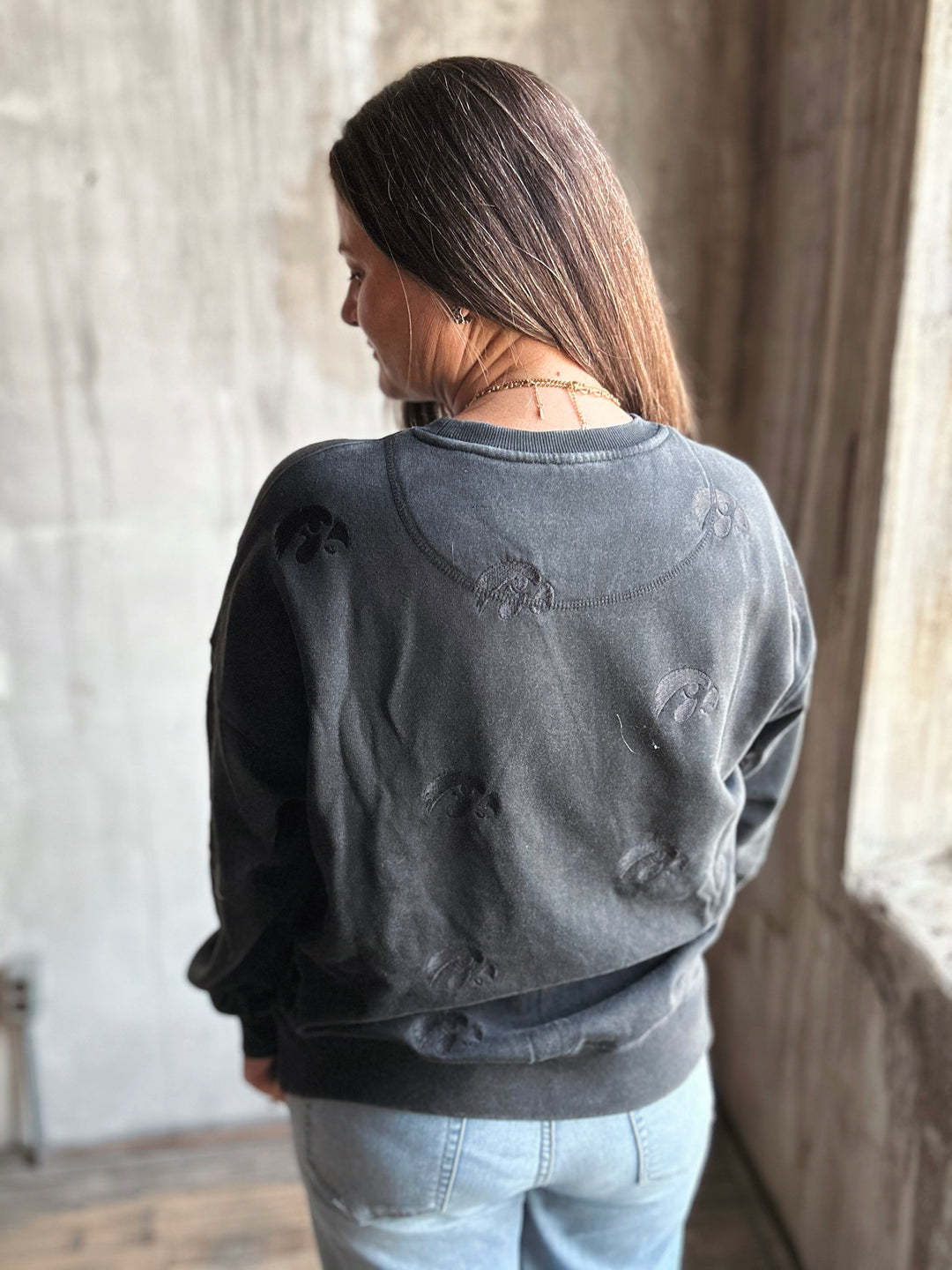 Person wearing a dark gray distressed sweatshirt in a room with neutral walls.