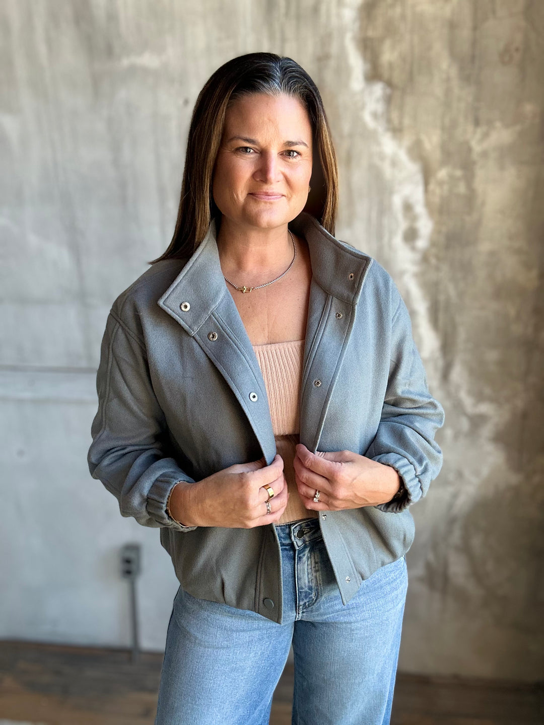 Woman in a slate blue snap-front jacket and light-wash jeans, front view