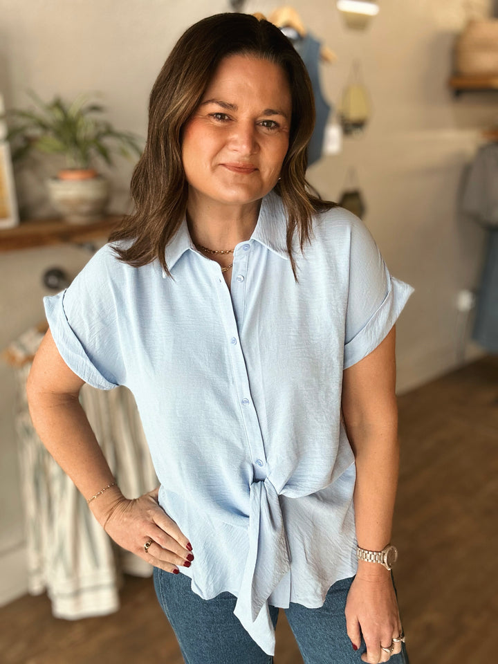Woman wearing a light blue shirt in a clothing store setting