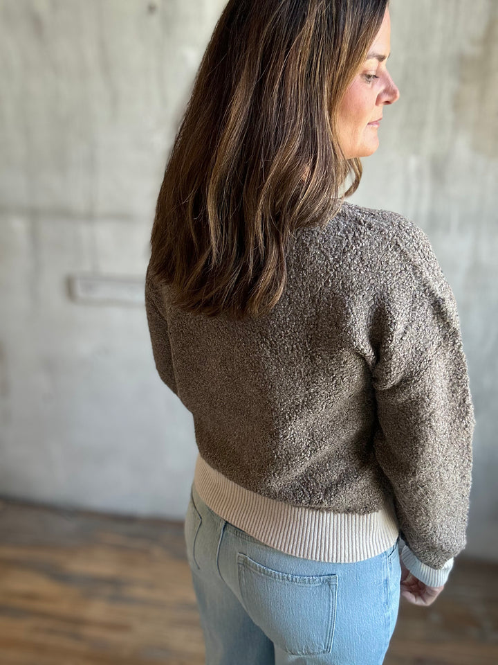 Back view of a brown speckled knit cardigan with cream hem