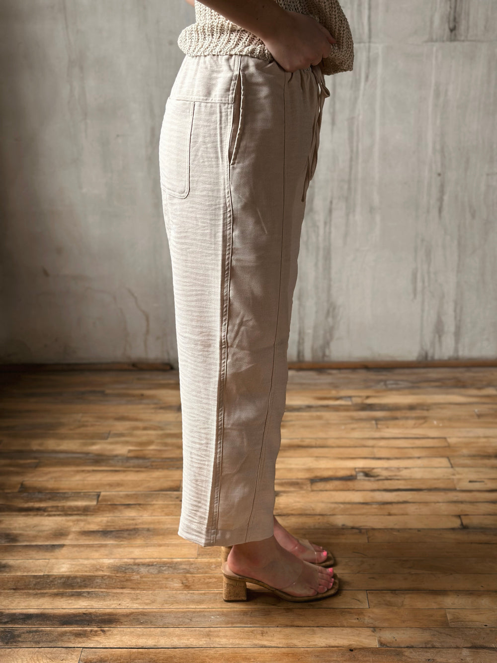 Person wearing beige pants standing on a wooden floor with a neutral wall background