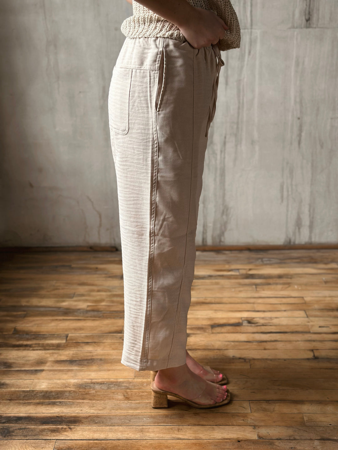 Person wearing beige pants standing on a wooden floor with a neutral wall background