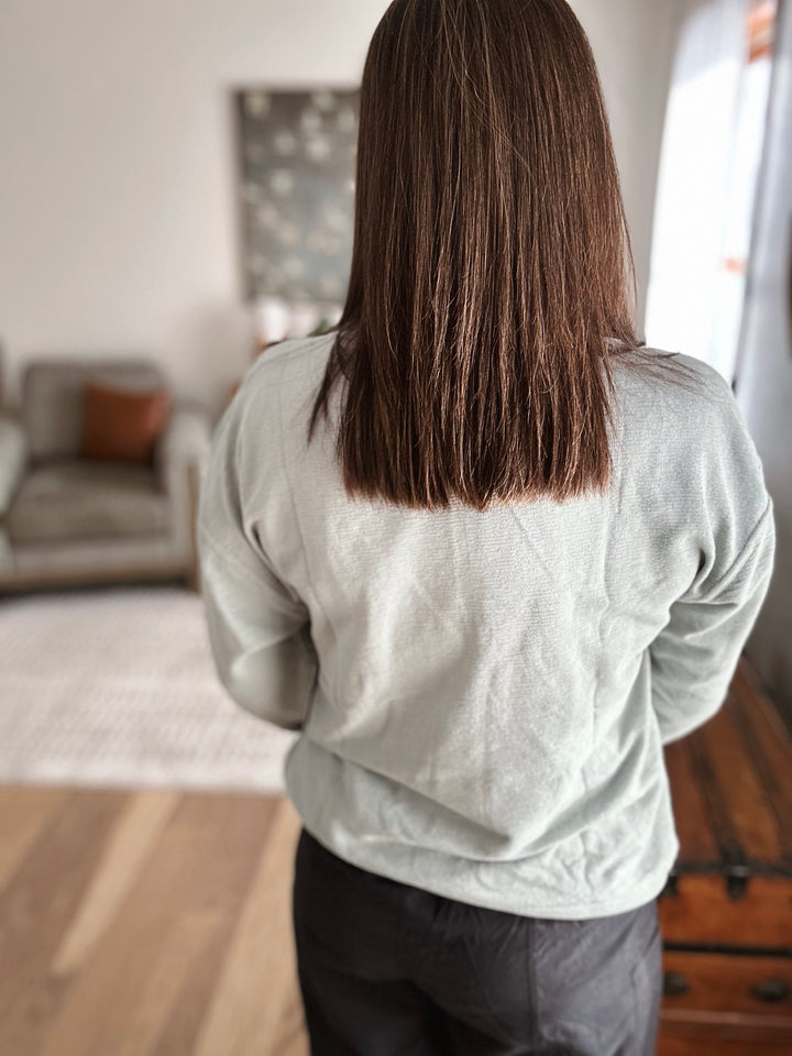 Person wearing a light gray sweatshirt in a living room setting