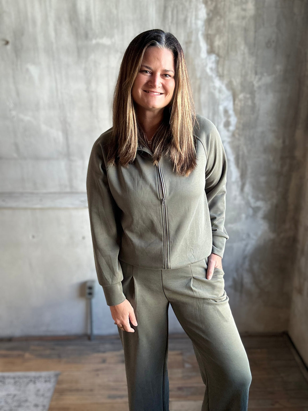 Woman in an olive green zip-up sweatshirt and matching pants, front view