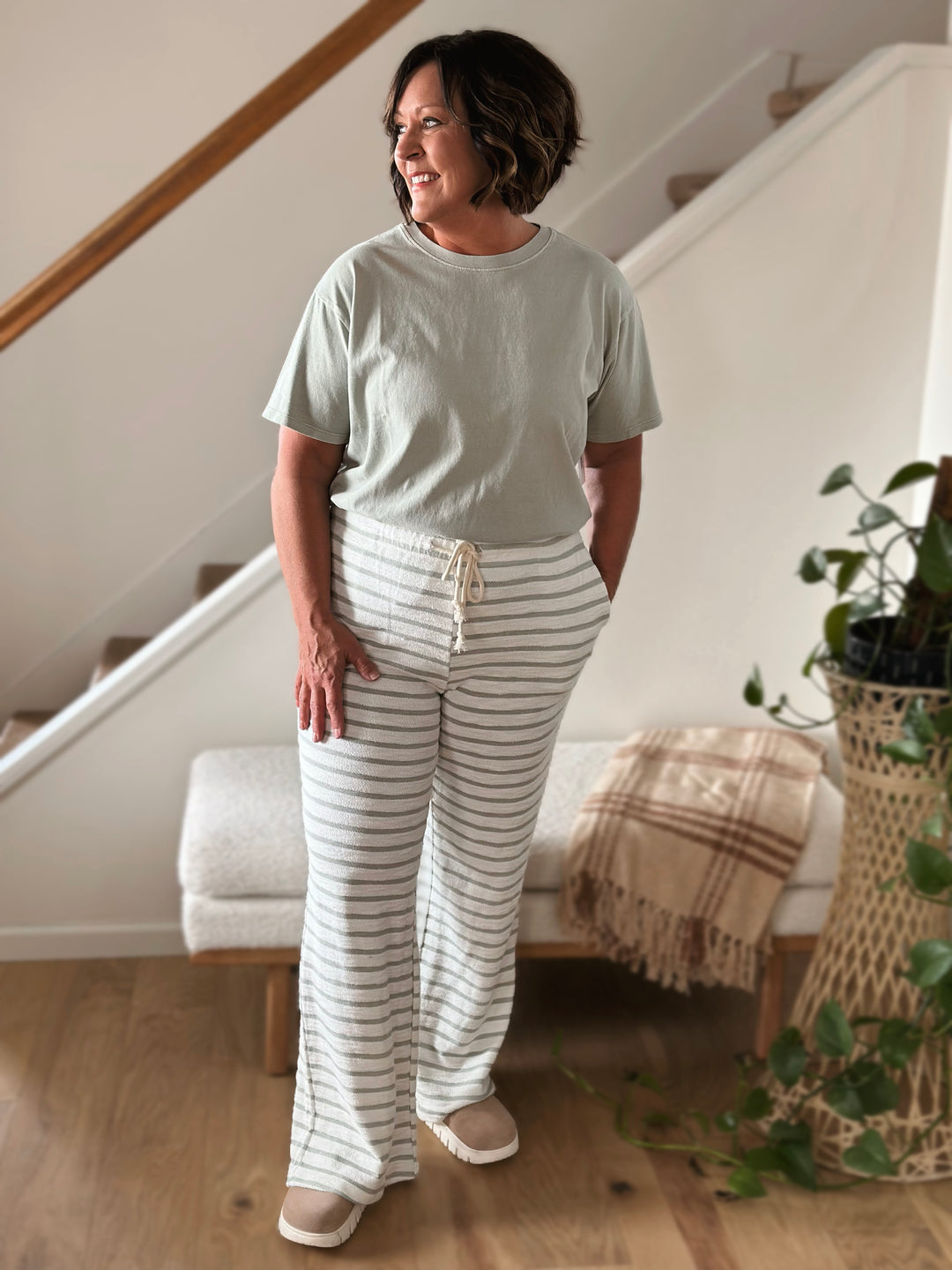 Woman wearing a light green t-shirt and white striped pants looking to her right.