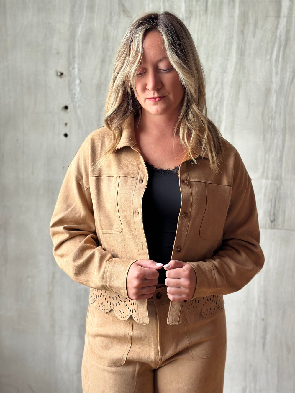 Woman wearing a tan suede-look shirt jacket with a laser-cut hem over a black tank