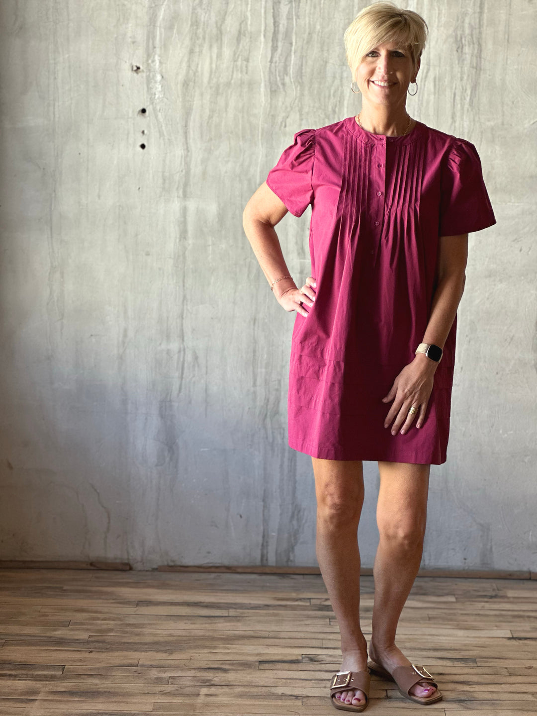 Front view of mini dress features a flattering pleated bodice and voluminous poplin puff sleeves. Deep Plum. 