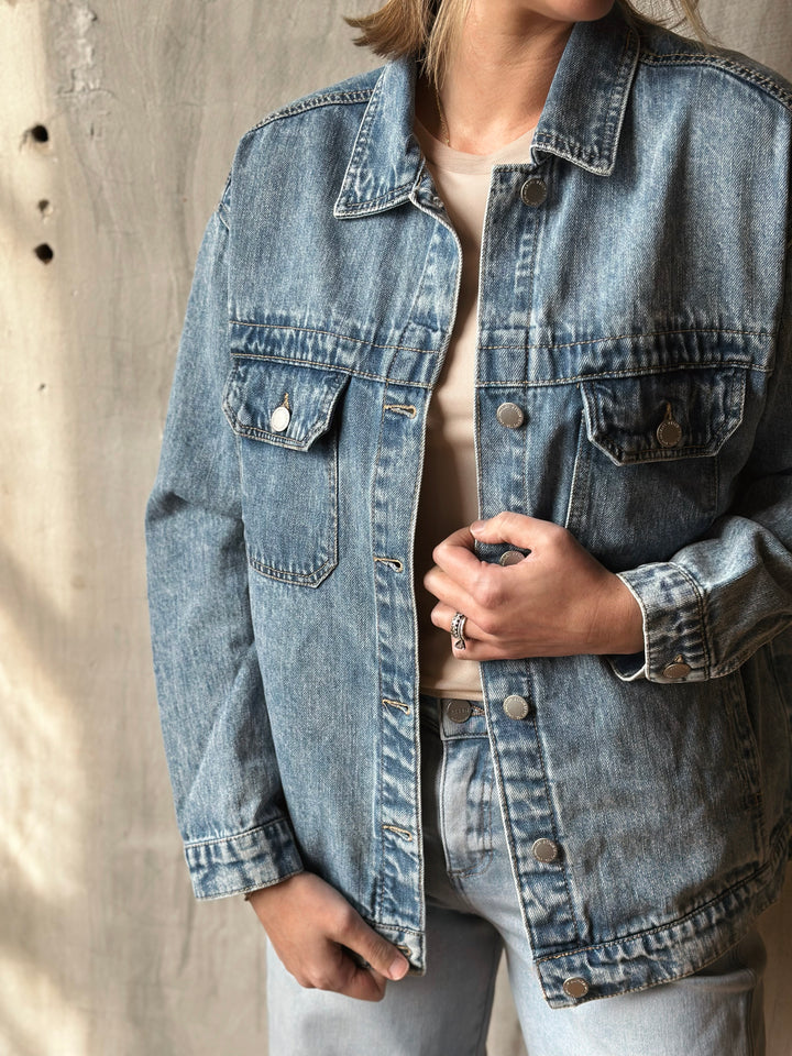 Person wearing a denim jacket against a neutral background