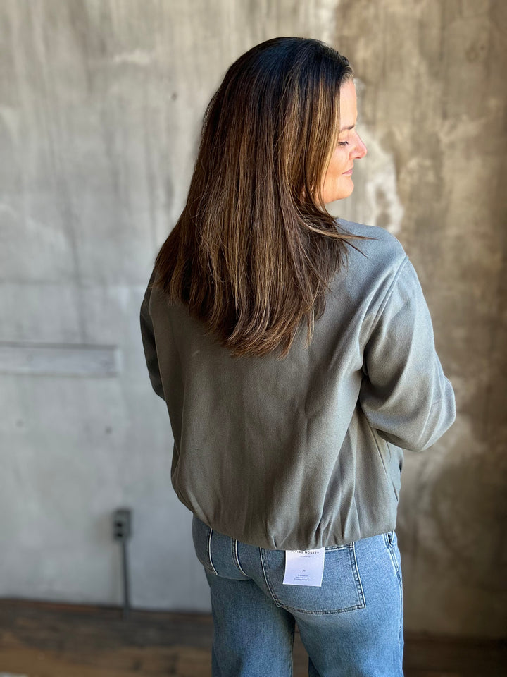 Back view of a slate blue jacket with a gathered elastic hem