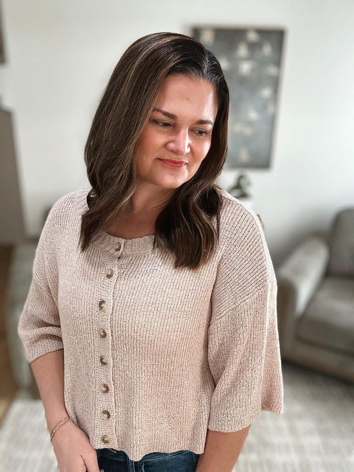 Woman wearing a beige cardigan in a living room setting