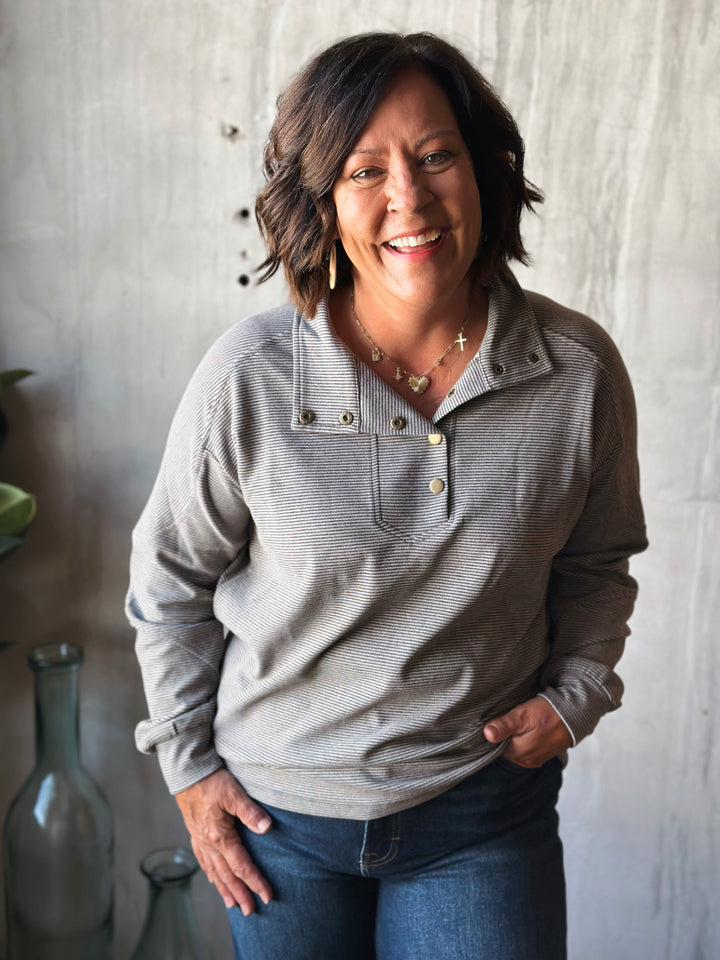 Woman wearing a gray sweater with a neutral background