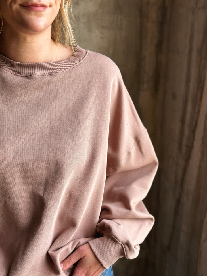 Person wearing a light pink sweater against a neutral background
