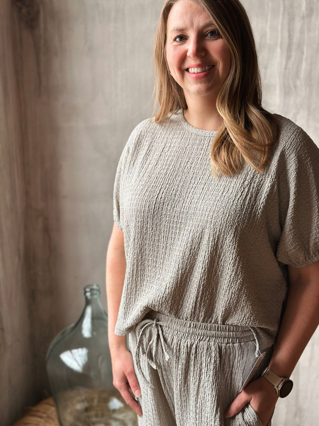 Woman wearing a textured sage shirt standing against a neutral background.