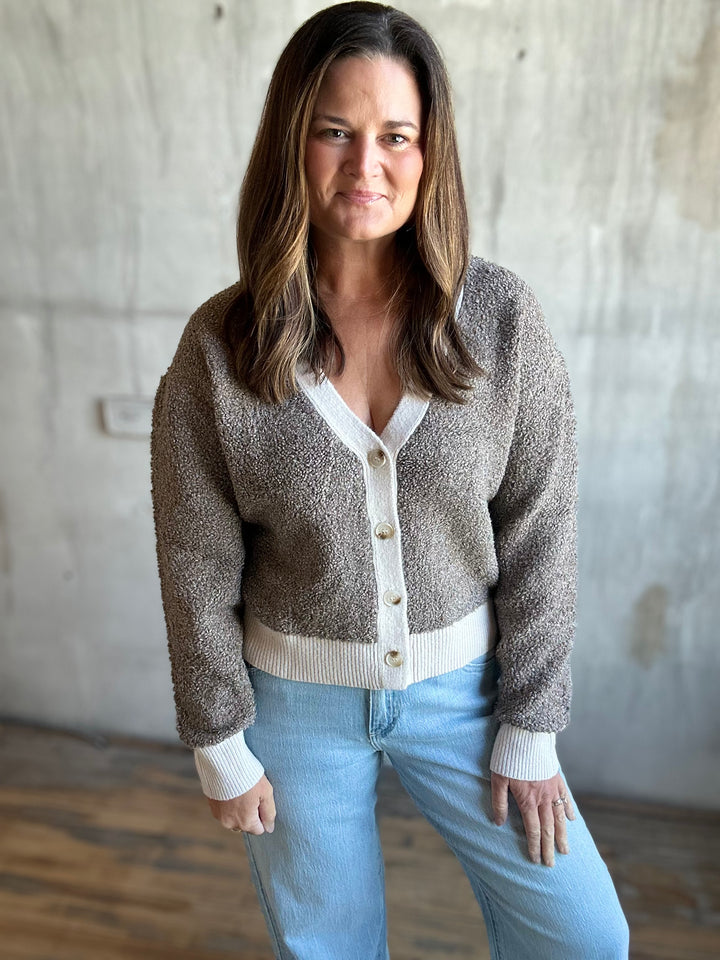 Woman wearing a speckled brown button-front cardigan with jeans