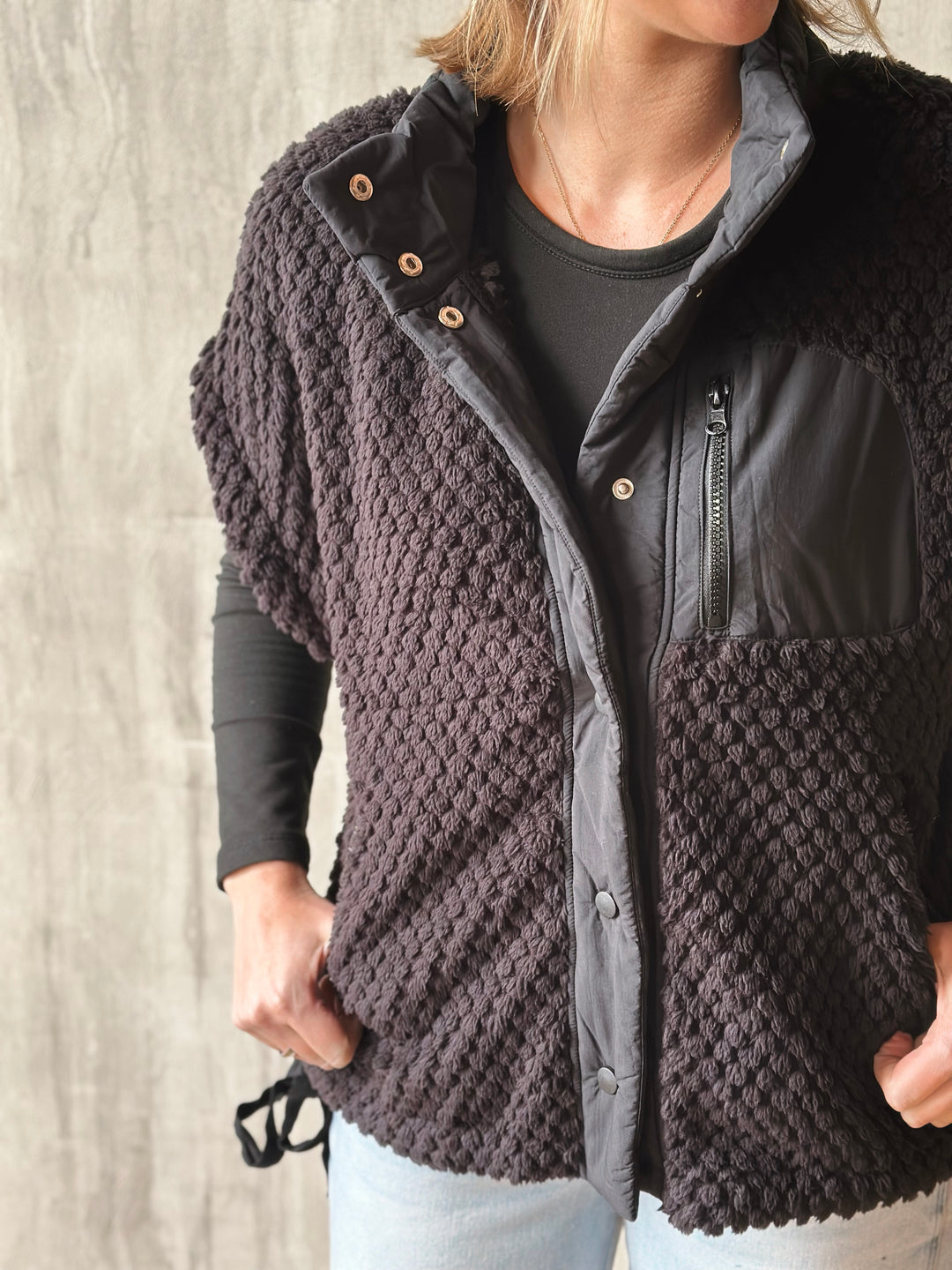 Dark brown textured jacket worn by a person against a neutral background