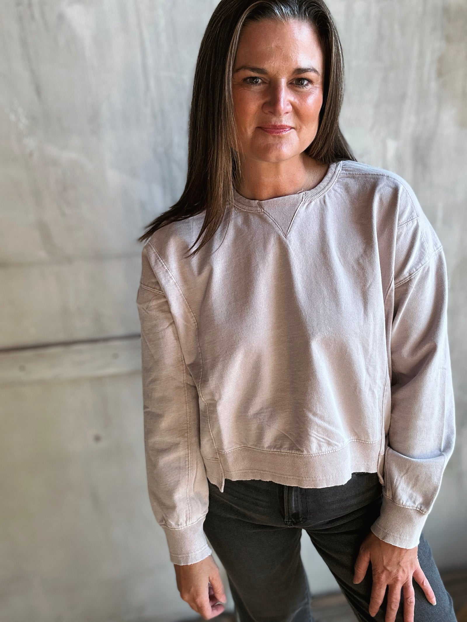 Woman wearing a beige sweatshirt against a plain background