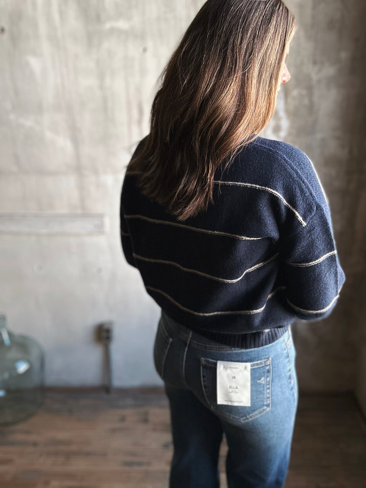 Person wearing a dark sweater and jeans with a blurred background