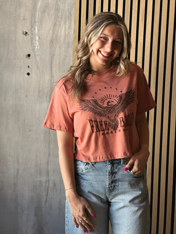 Front view of model wearing a mauve shirt with Free Bird graphic tee with puff print design