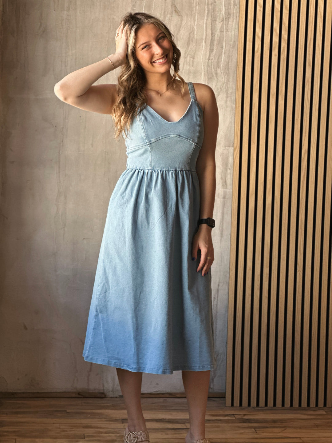 Front view of model wearing a flare dress that has a stretch denim fit with a sweetheart neckline, wide straps, and it is a light Denim color 