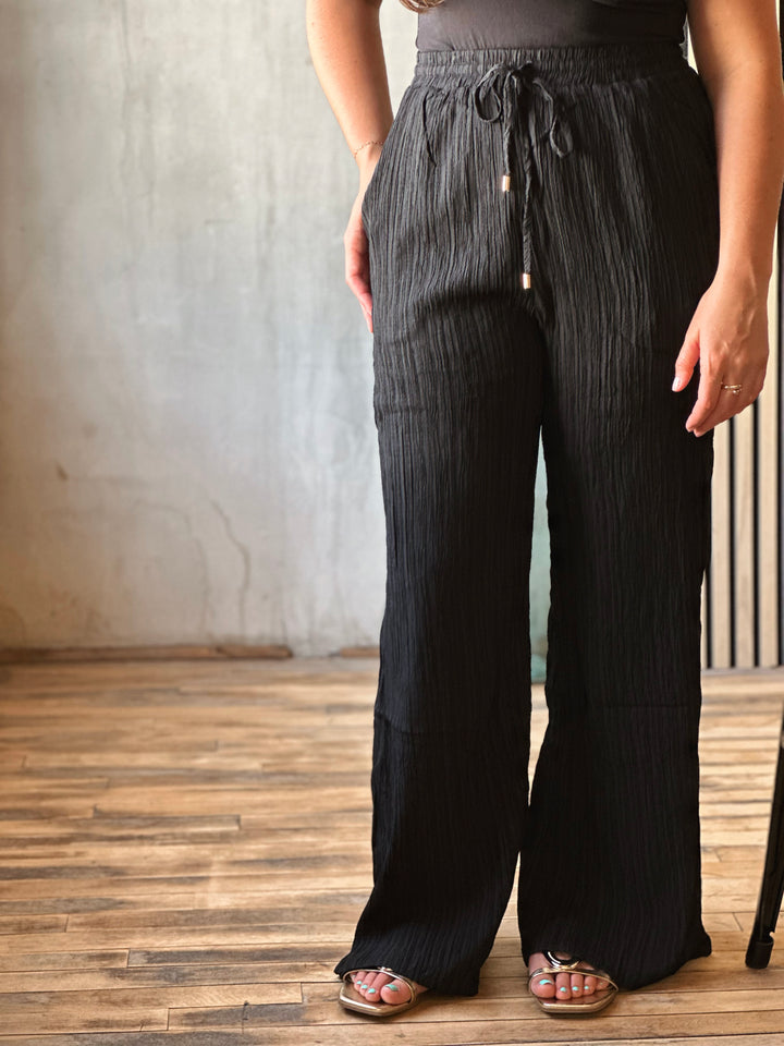 Person wearing black wide-leg pants with a neutral background