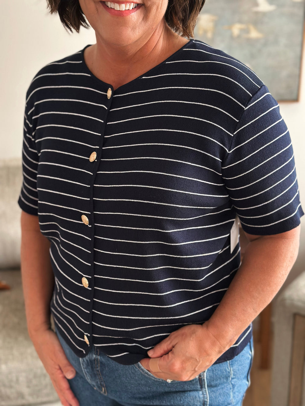 Person wearing a navy and white striped shirt with buttons, standing indoors.