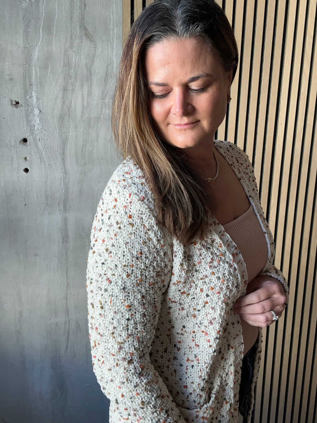Close-up of a cream cardigan with a black-and-tan speckled knit