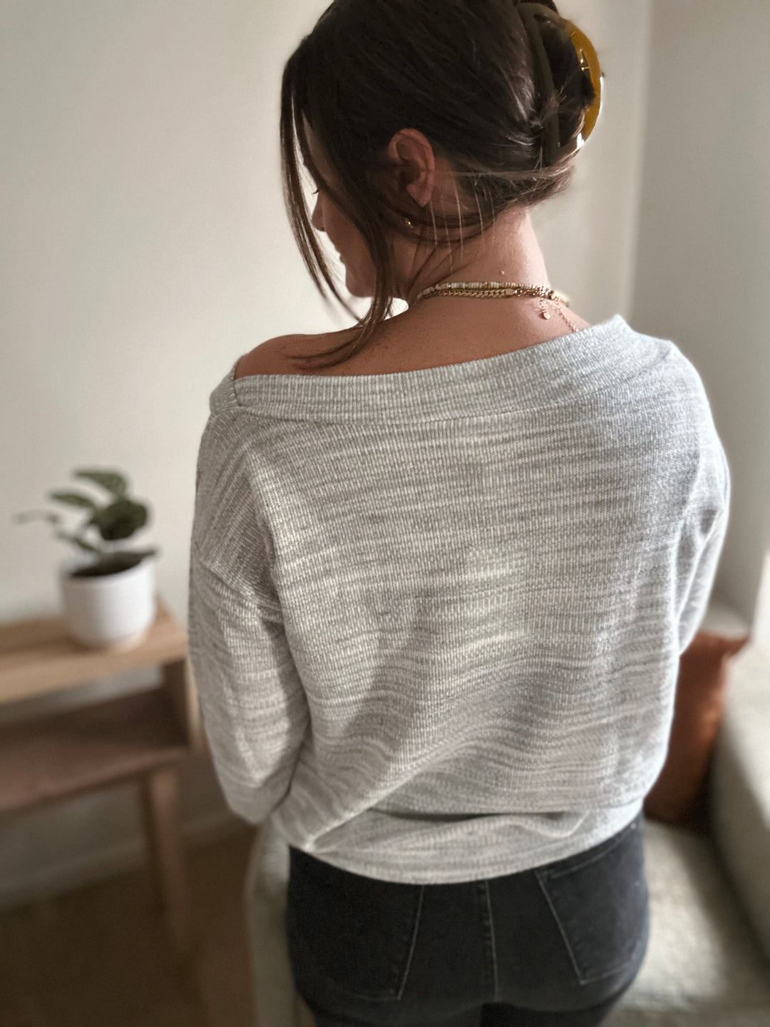 Person wearing a light gray sweater in a casual indoor setting